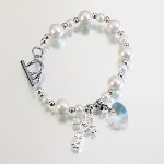 This beautiful Rosary bracelet measures 8" long. Its length is made up of a series of off-white beads (in two sizes) and smaller silver-plated beads. A clear acrylic heart charm and silver-plated cross ornament hang from the bracelet.